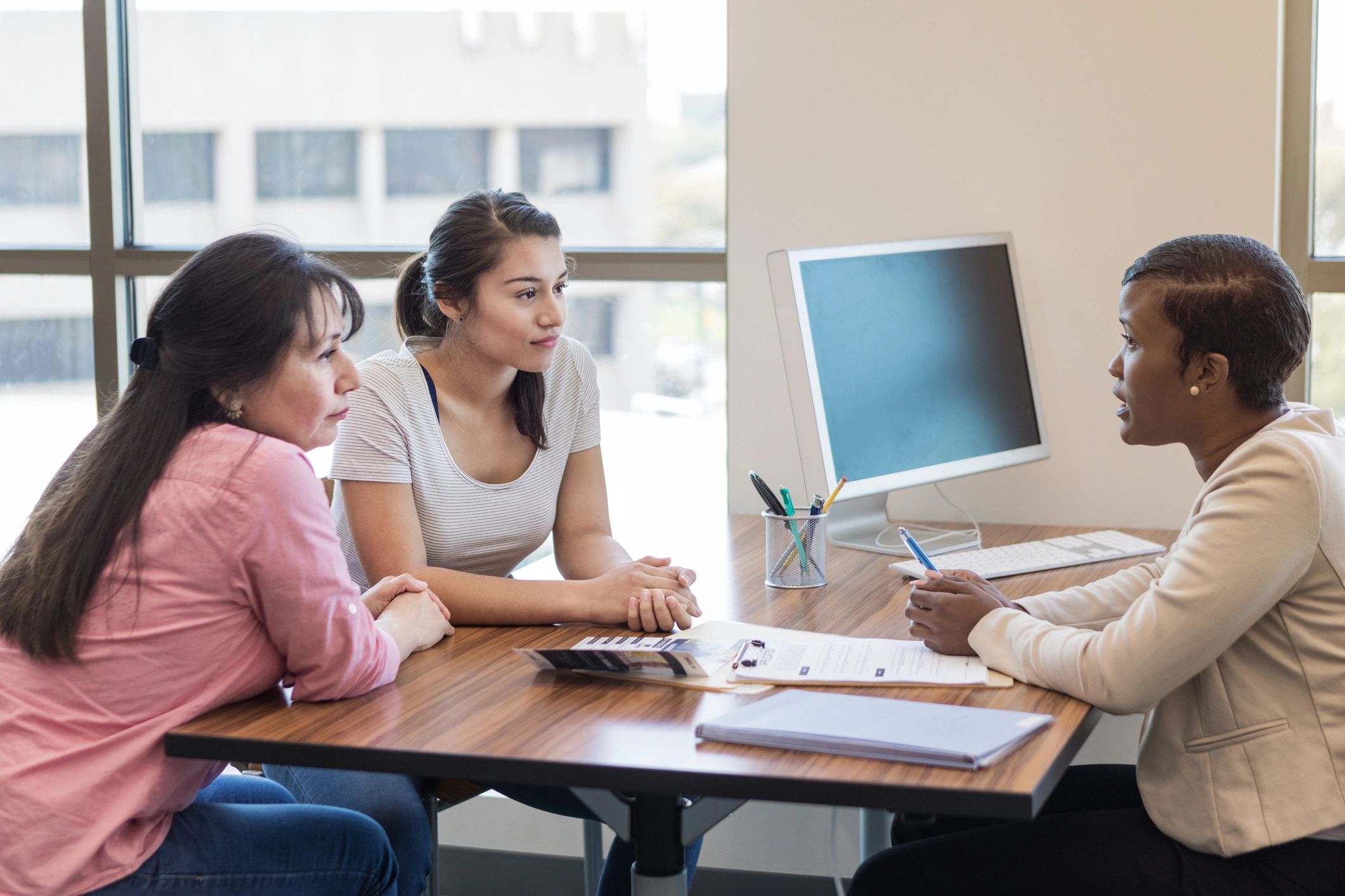 Two women consulting a professional in an office setting.