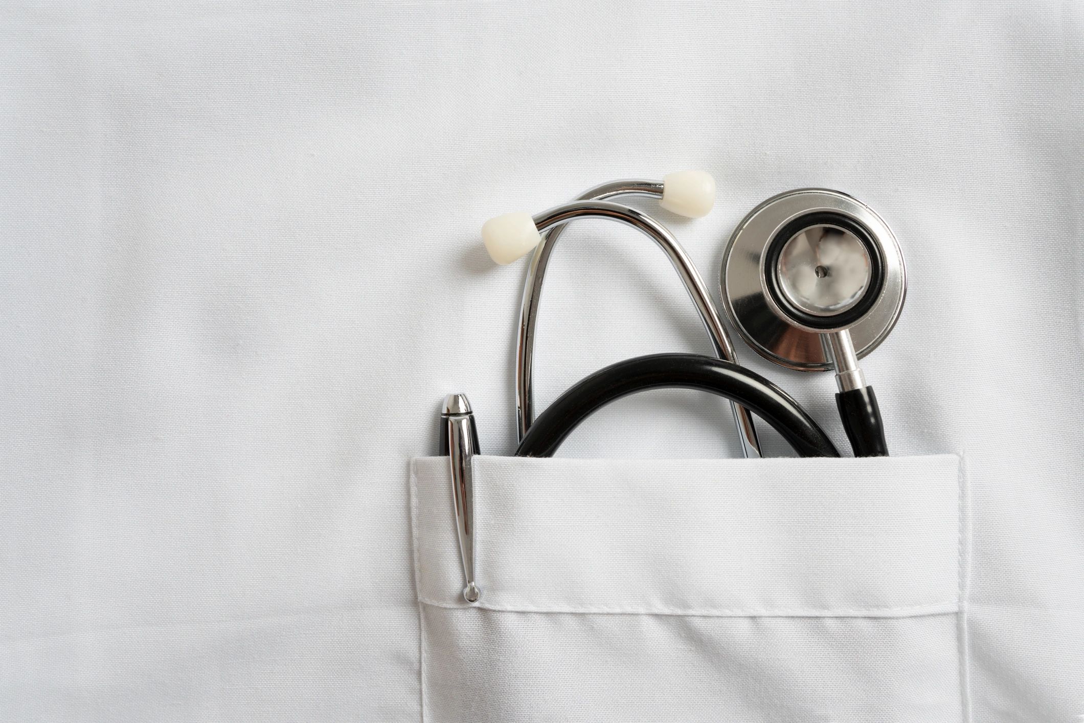 Stethoscope peeking out of a white lab coat pocket.